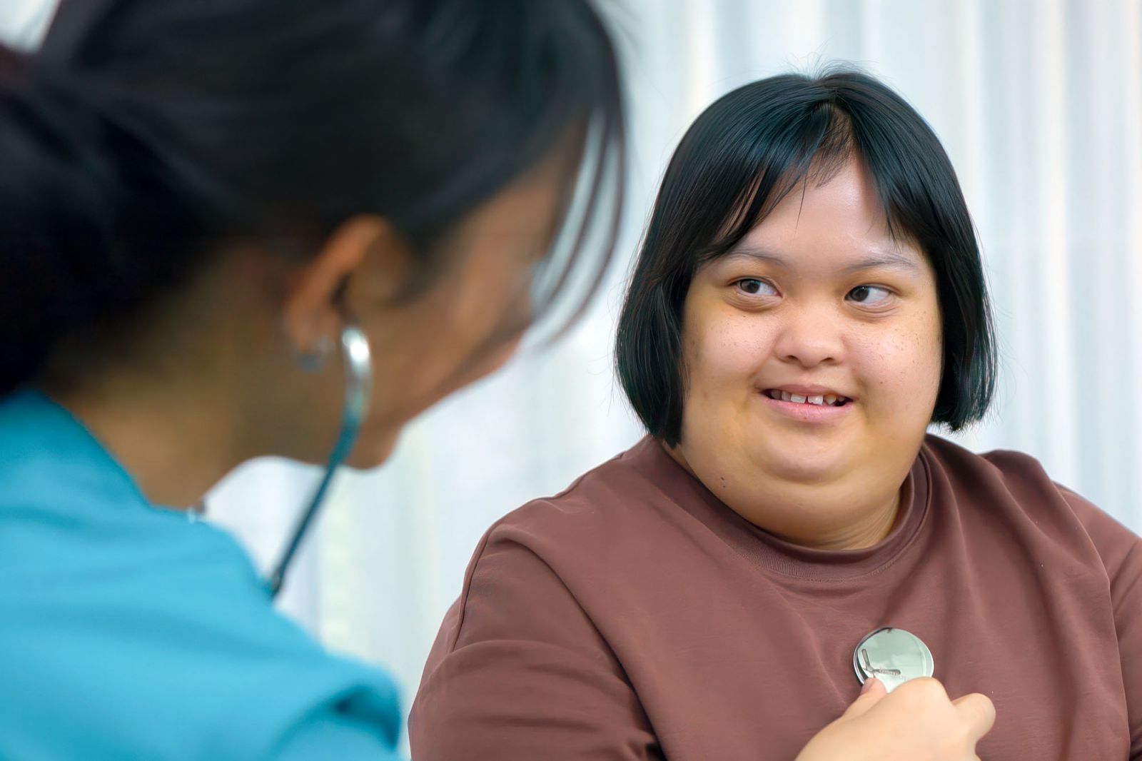 Young man with Down syndrome cooking in contemporary kitchen with female assistant