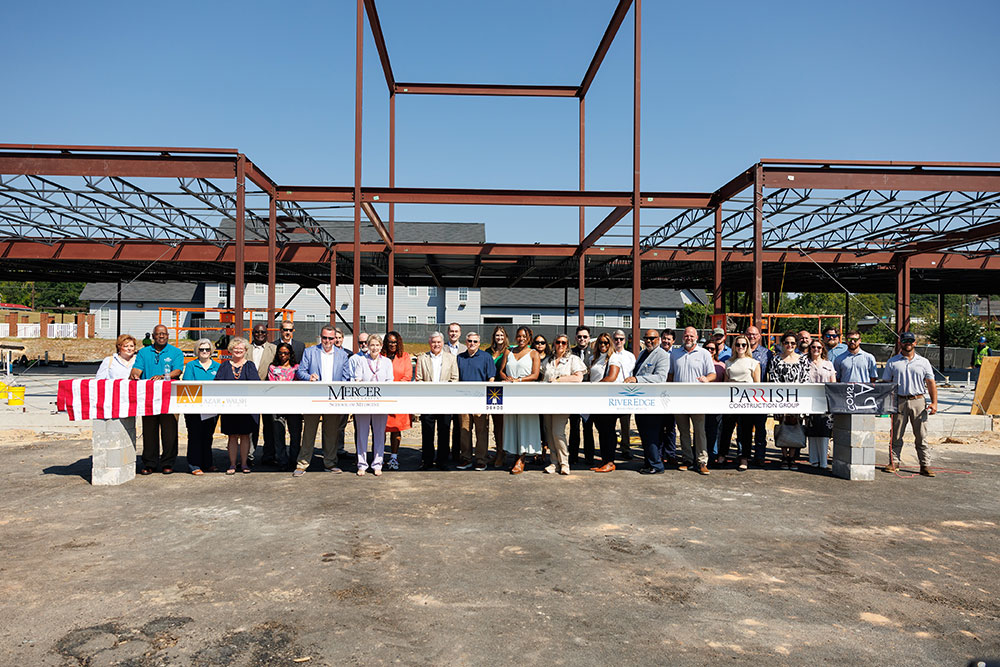 Project partners pose with a ceremonial beam at the construction site for a new Crisis Services