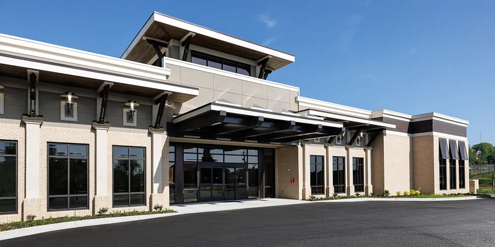 Modern medical facility with large glass windows and wide entrance under clear blue sky